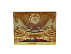 A magnet of a picture facing Stern Auditorium from Perelman Stage with a piano in the center of the stage.